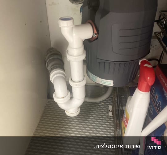 צנרת מתחת לכיור עם מוצרי ניקוי